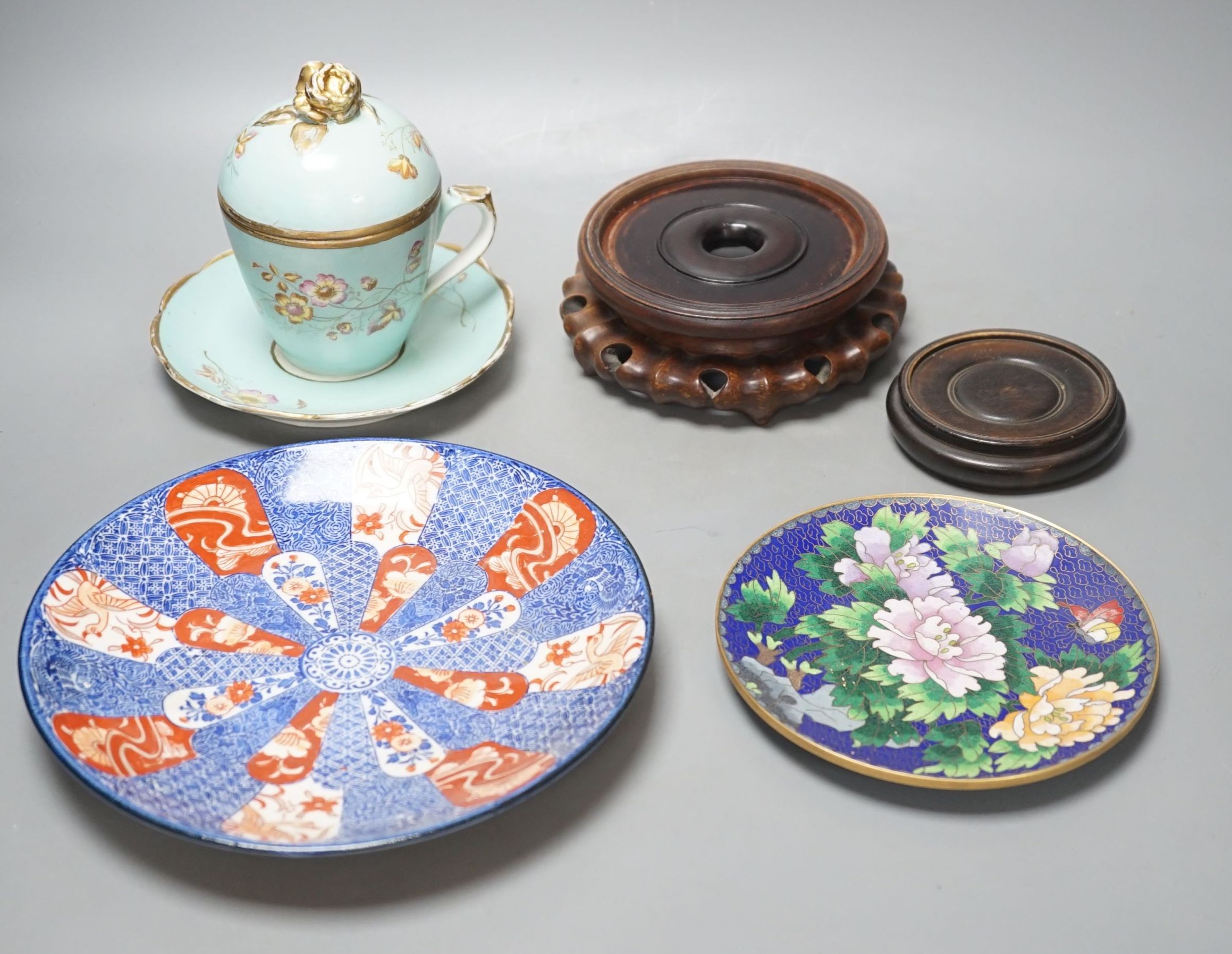 A Continental porcelain jam pot, 15cm tall, and cover with stand, together with 2 Chinese hardwood stands, enamelled plate and another (7)